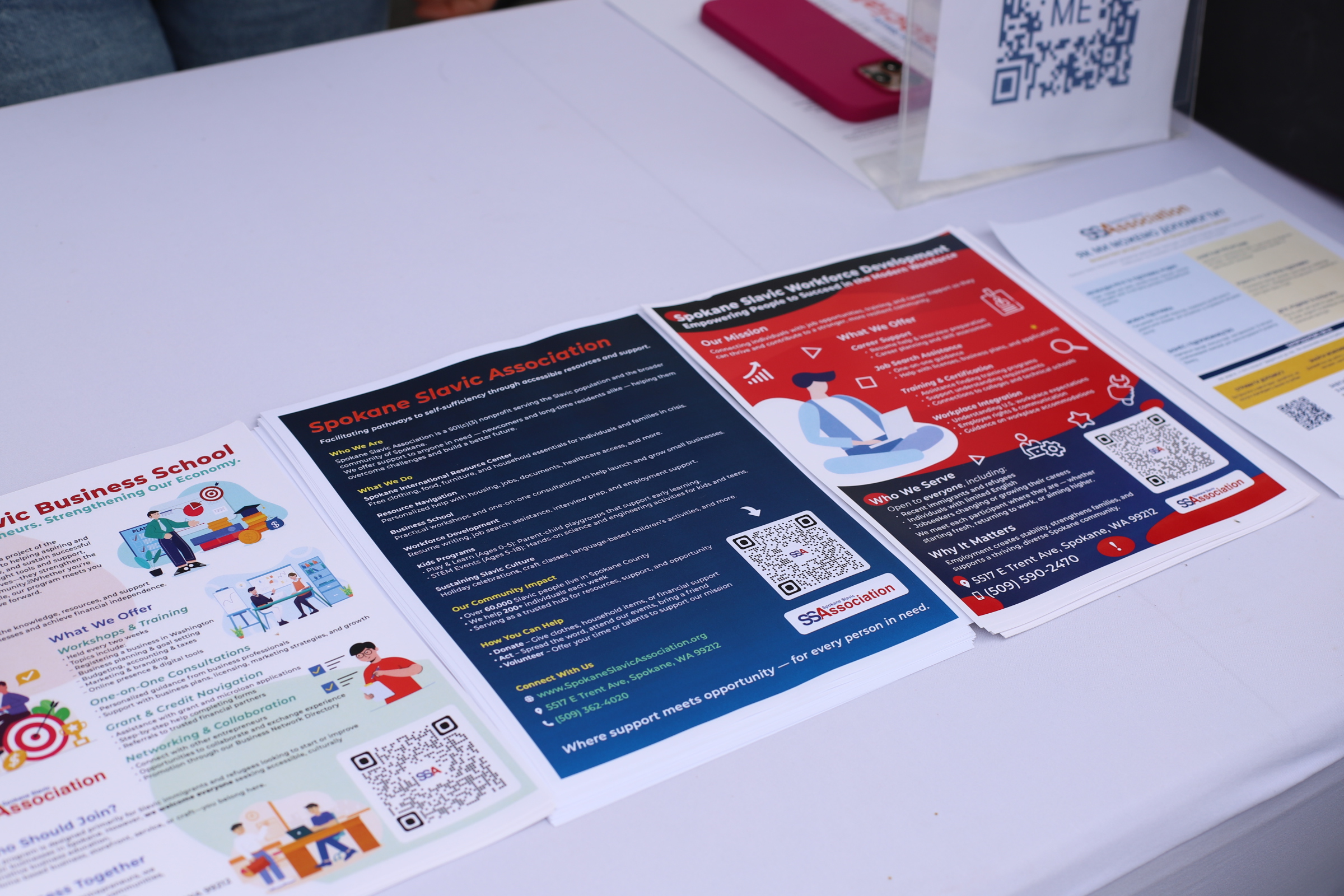 Multilingual public information flyers on a table at a community event.