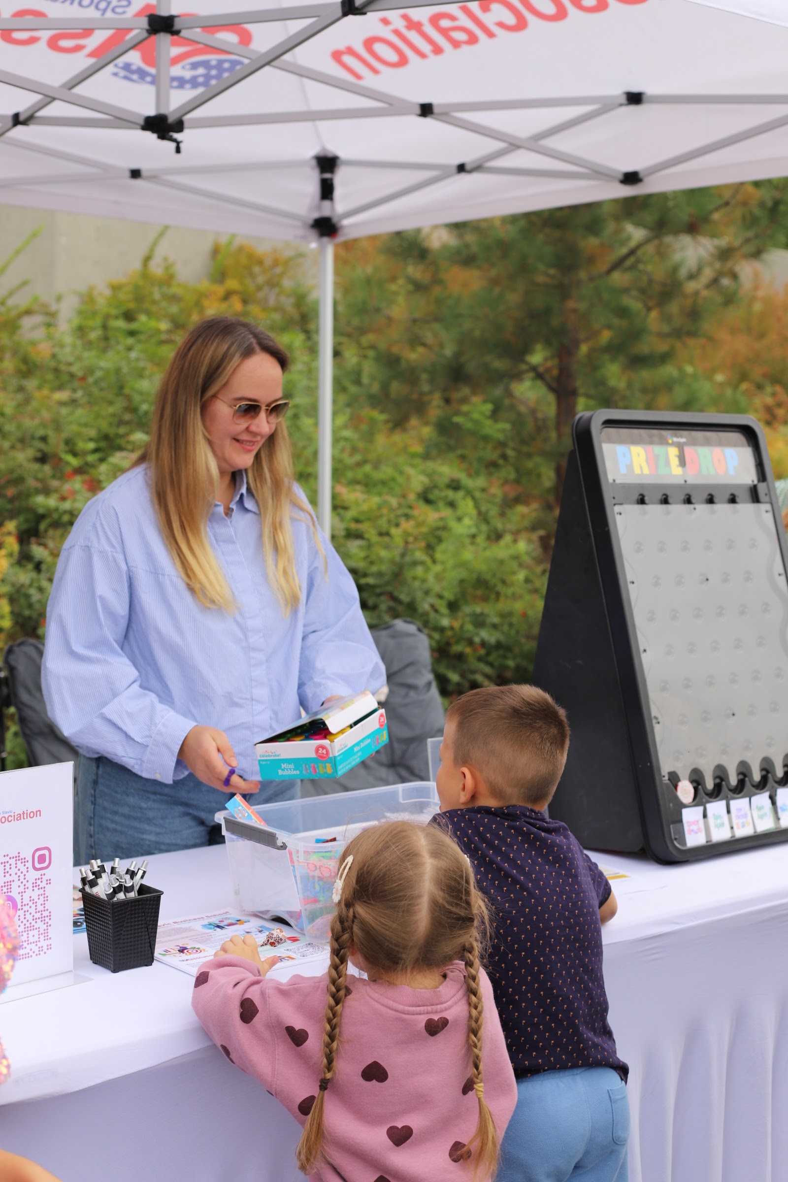 An outreach volunteer talks with a parent and child at an information table.
