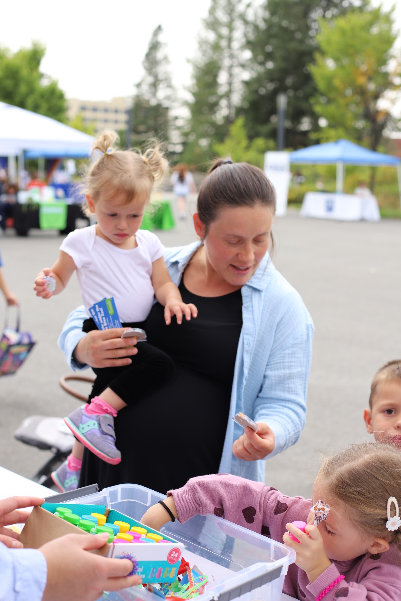 A parent and child visit partner organization tables at a community event.