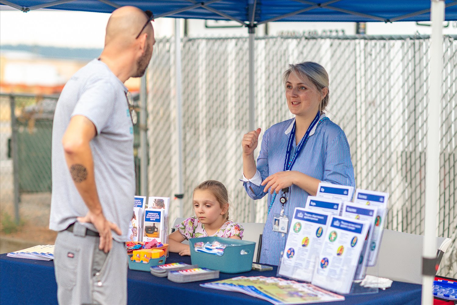 An SSA staff member explains resource materials to a visitor at an information table.