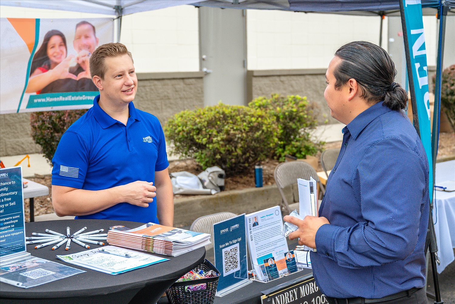 A local business representative talks with a community member at an information table during an SSA community event.